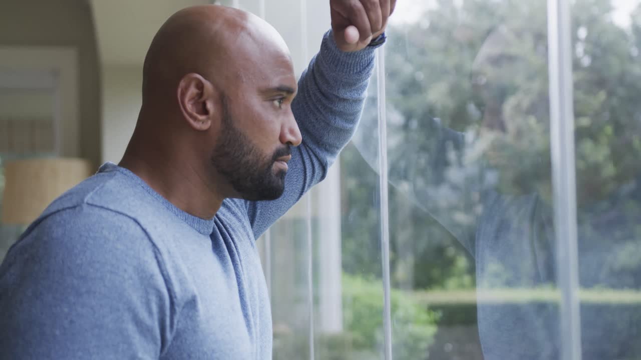 Profile of biracial man looking out window at home
