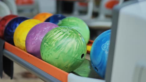 blue ball returns smoothly down track onto rack among vibrant bowling balls set