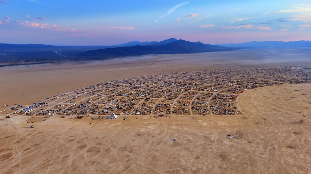 Drone view of the circular layout of the Burning Man desert camp surrounded by vast playa and mountains