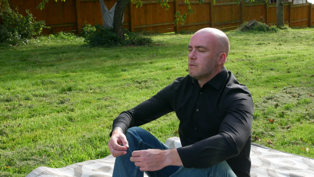 A man meditating breathing deeply practicing mindfulness and meditation outside in a yoga position in nature