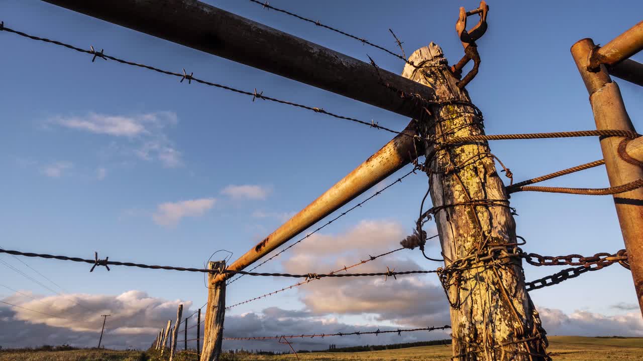 구름이 철조망 울타리 전경이 있는 몰로카이 하와이 섬의 수평선을 가로질러 움직입니다.