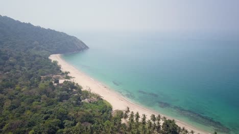 Aerial-view-of-long-white-sandy-beach-with-clear-waters-and-lush-vegetation-in-Thailand---camera-tracking-pedestal-down