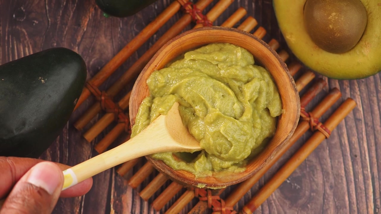 Nabírání čerstvého guacamole z dřevěné misky