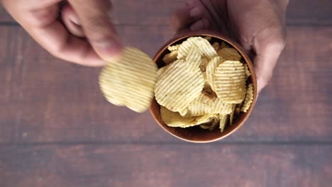persona comiendo papas fritas de un cuenco de madera