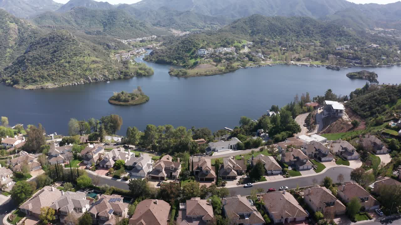 Aerial wide reverse pullback shot of the Lake Sherwood Reservoir in Southern California. 4K at 30 FPS