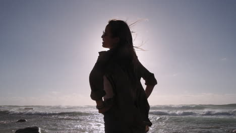 Disparo-A-Cámara-Lenta-De-Silueta-De-Mujer-Sonriente-Posando-En-La-Playa-Durante-El-Sol