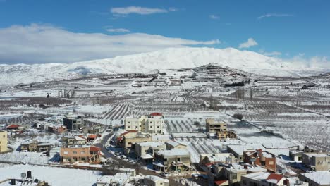 Casas-En-La-Ciudad-De-Buqata-Con-Nieve-En-Los-Techos-En-Un-Camino-Despejado-Con-La-Montaña-Hermon-Al-Fondo-En-Un-Día-Soleado