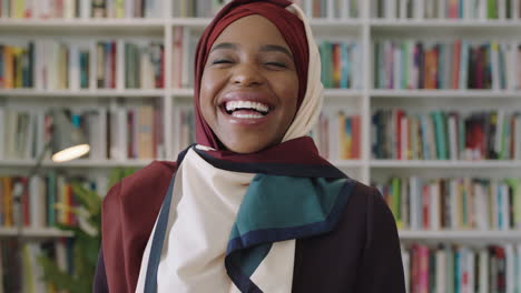 Retrato-De-Una-Joven-Y-Encantadora-Mujer-Afroamericana-Riéndose-Mirando-A-La-Cámara-Estudiante-Parada-En-La-Biblioteca