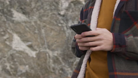 close up view of teenage boy hands using smartphone on the mountain