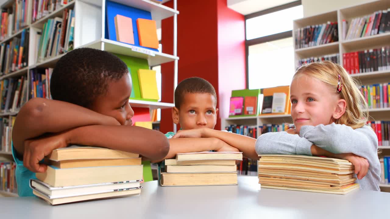 School kids leaning on stack of books in library