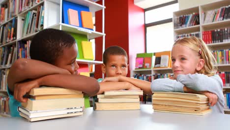 School-kids-leaning-on-stack-of-books-in-library