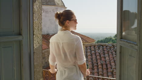 Glückliche-Frau,-Die-Ihr-Smartphone-Nutzt,-Um-Ein-Foto-Zu-Machen-Und-Es-Zu-Genießen,-Sommerurlaubsreiseerlebnisse-Zu-Teilen-Und-Die-Wunderschöne-Aussicht-Auf-Dem-Balkon-Mit-Sonnenbrille-Zu-Fotografieren