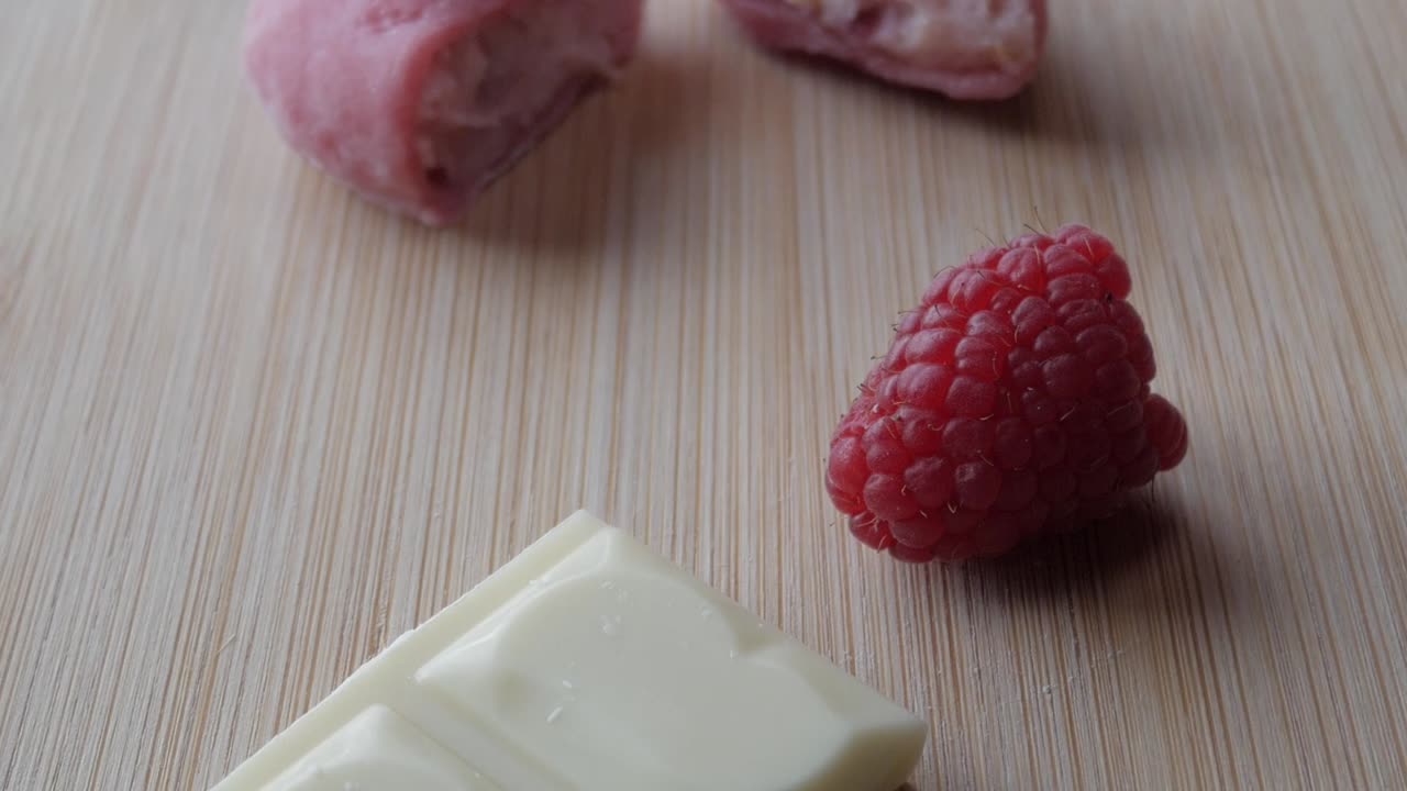 White chocolate and fresh raspberries placed on a wooden table, creating a delicious treat vibe