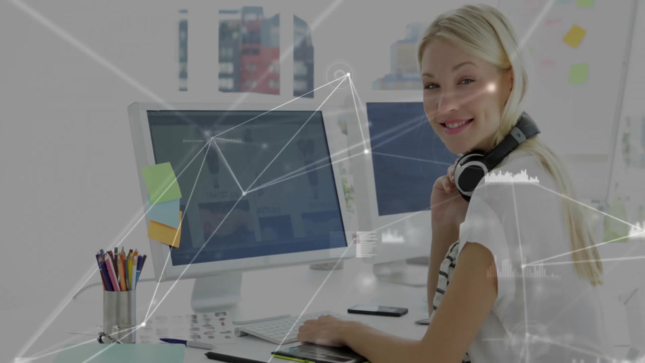 Ung kvinde arbejder ved computer på moderne kontor med digital grafik