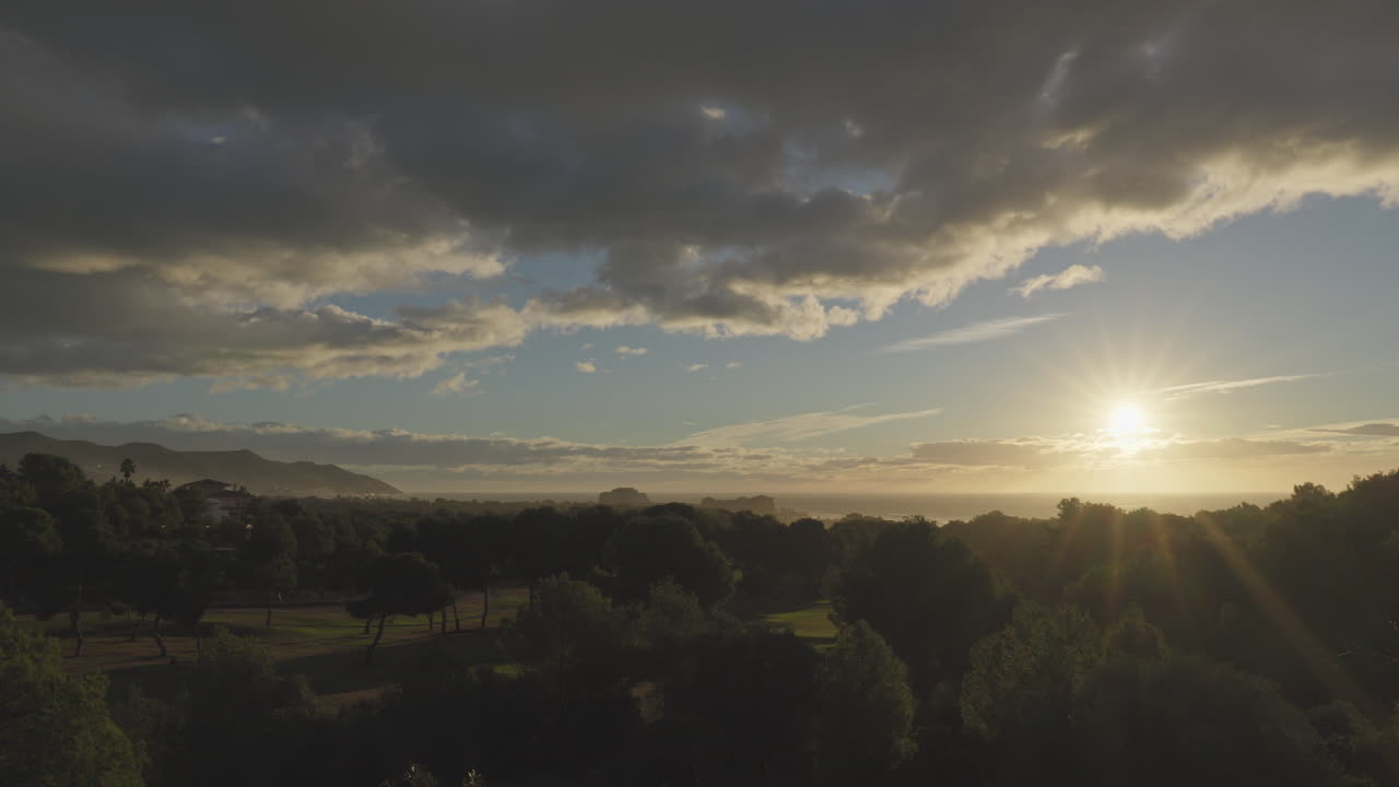 un lapso de tiempo del amanecer del campo de golf verde con las montañas y el mar al fondo