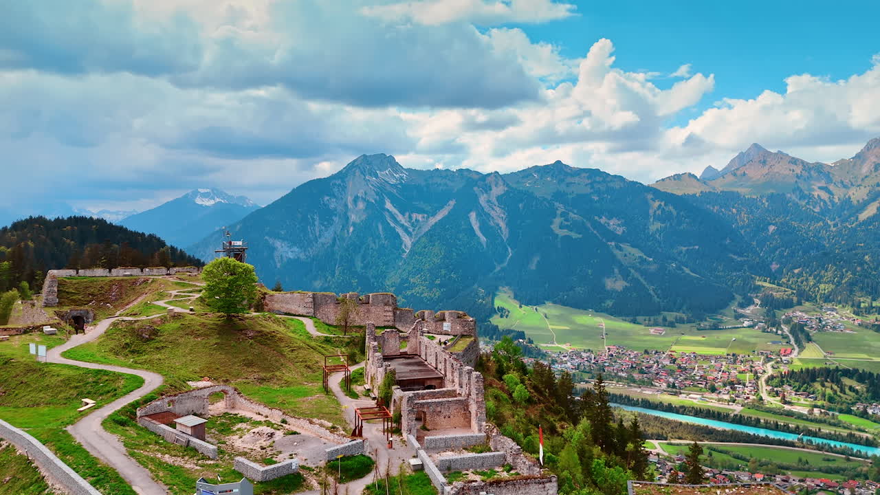 Approaching the ruins of Ehrenberg Castle in Reutte, Tyrol, Austria. Spectacular mountains at backdrop under the grey cloudscape. Aerial perspective.