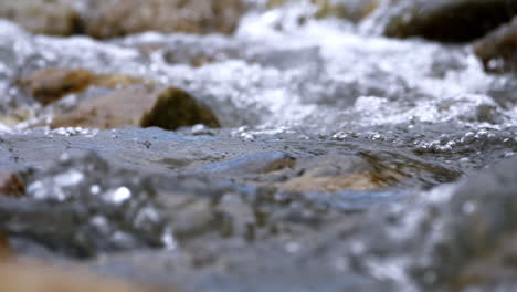 Clear-stream-running-through-stone-boulders-Abundant-river-flowing-in-slow-motion