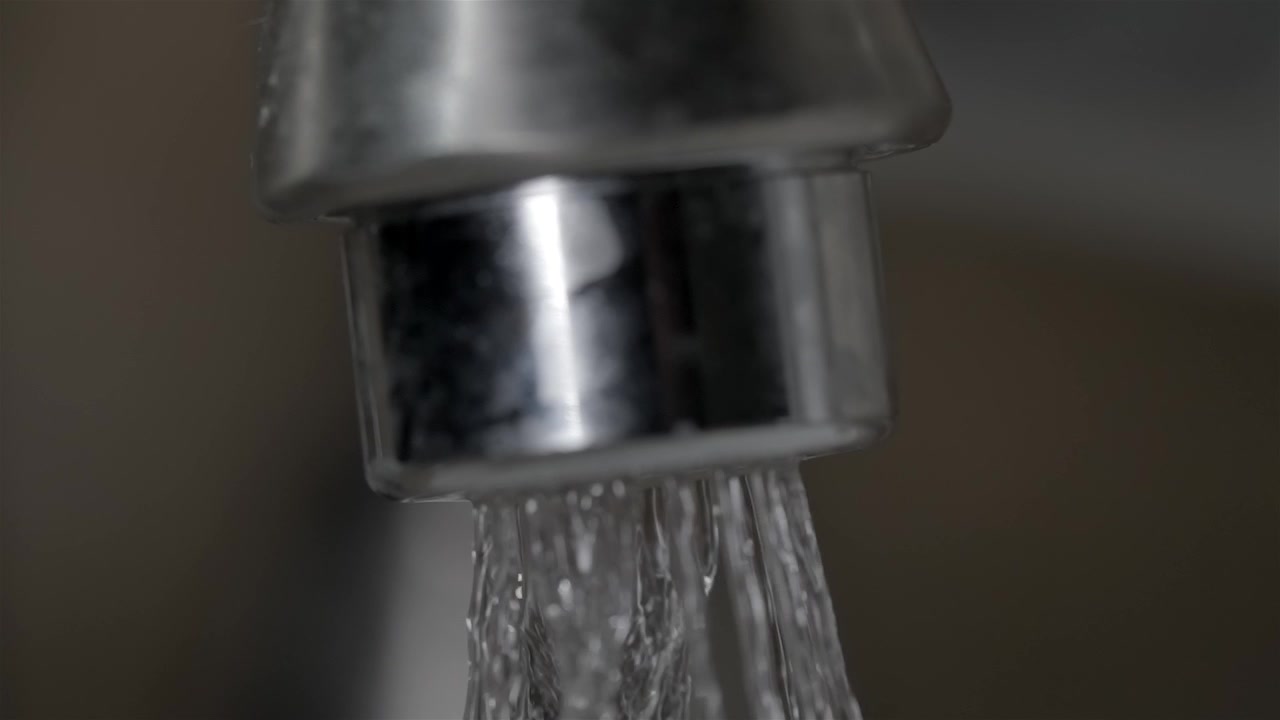 Primo piano di un getto d'acqua fredda e limpida dal rubinetto del lavandino del bagno