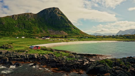 aerial drone shot of the picturesque green landscape of the lofoten islands, norway. bird's eye view of the white sanded beach, sea mountain in the background.