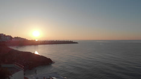 Drone-reveals-beautiful-sunset-pier-and-bay-,-off-the-coast-sea-and-sky