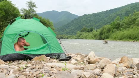 the tourist wakes up in a tent near a mountain river the tourist wakes up in a tent near a mountain river the concept of mountain recreation in nature