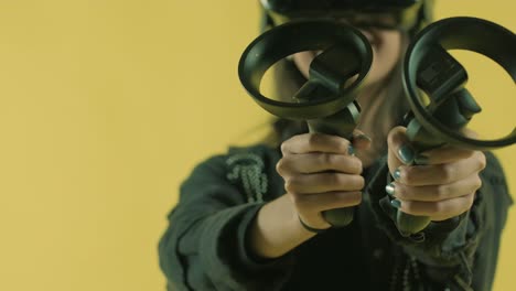 young woman playing with controllers and wonders how amazing in the vr headset. virtual reality helmet on the yellow background.