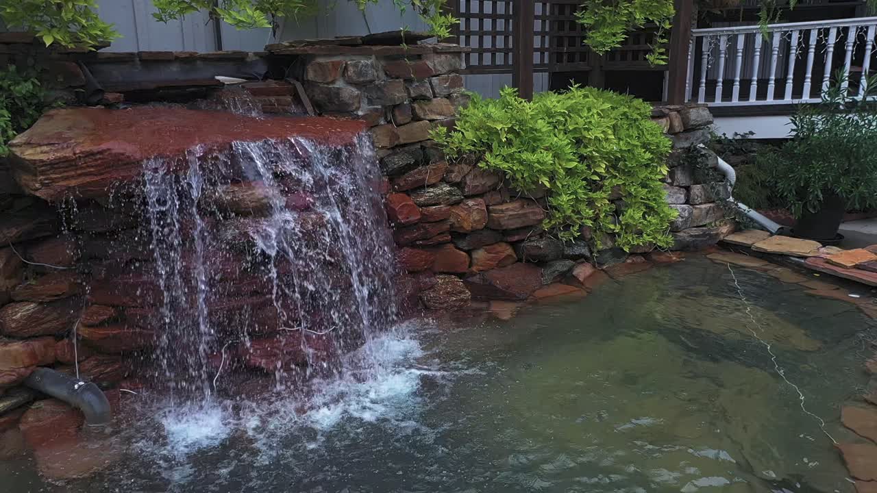 Backyard Waterfall Flowing Over Stacked Rocks Into Clear Pond In Atlanta, Georgia. panning shot