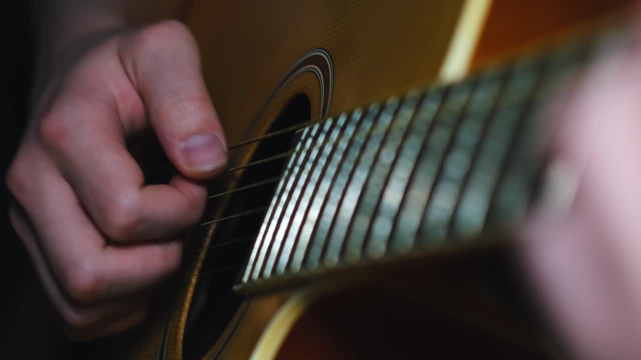 primer plano de manos tocando una guitarra acústica