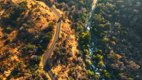 car moving by the dangerous road on the mountain. quick river with multiple rapids flowing at the foot. top view.