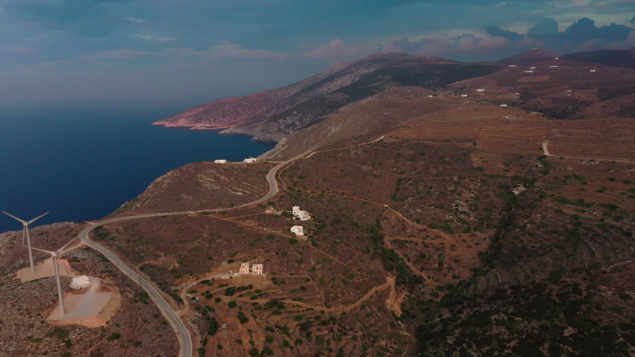 toma aérea de un paisaje insular de las cícladas con dos turbinas eólicas