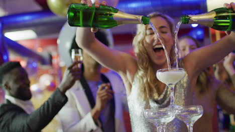 video of happy caucasian woman pouring a champagne fountain into glasses at nightclub