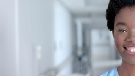 Portrait-of-happy-african-american-female-doctor-smiling-in-corridor,-copy-space,-slow-motion