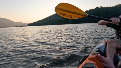 person kayaking on a lake at dusk