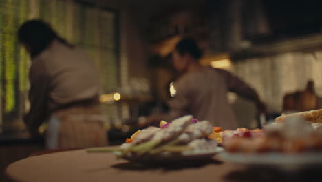 delicious plated appetizers in focus while two women work in a warm, busy kitchen