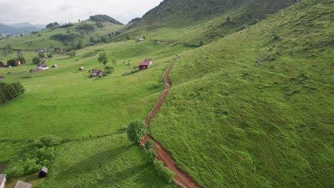 a serene rural village with a winding road among green hills, aerial view