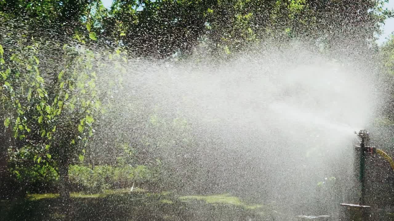 Moderno dispositivo per l'irrigazione del giardino. Irrigatore da prato che spruzza acqua sull'erba verde e fresca in giardino.