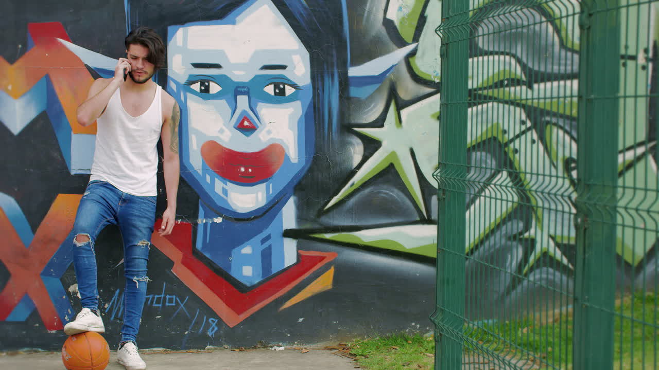 hombre guapo mirando el celular con un graffiti como fondo