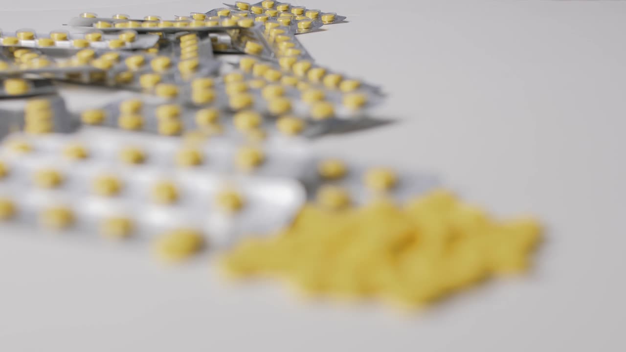 Yellow pills with packages on white background