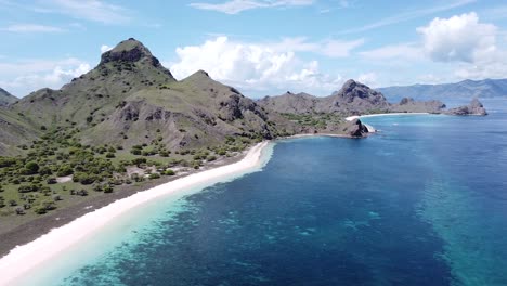 drone shot of tropical beach and forest mountains and ocean water in komodo national park, indonesia