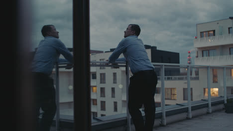a sad man in a shirt smokes a cigarette on the balcony