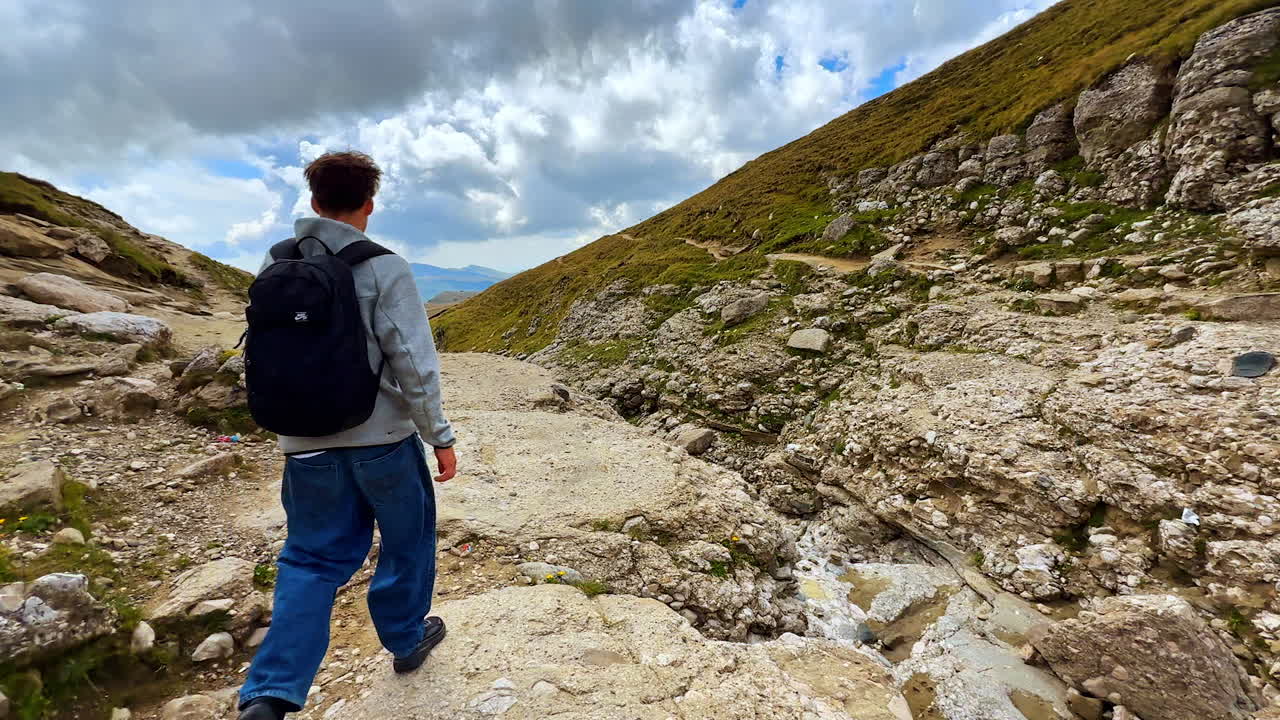 Rocky mountain path with cloudy sky in Bucegi Mountains. Path through rocky terrain in Bucegi Mountains under dramatic clouds
