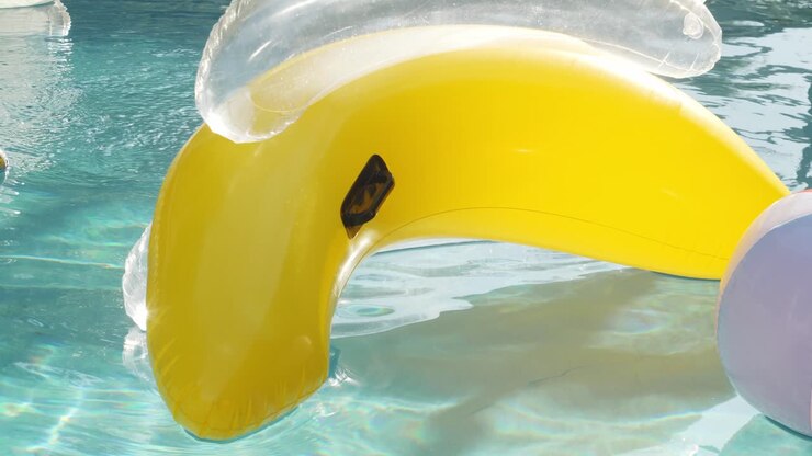 A banana shaped floaty moves through the sunny water in slow motion