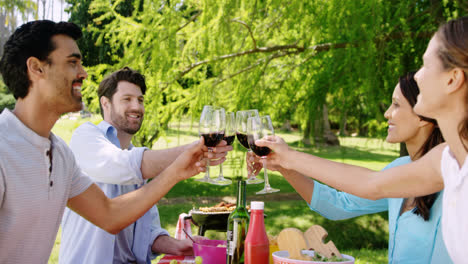 parejas brindando vasos de vino rojo en el parque