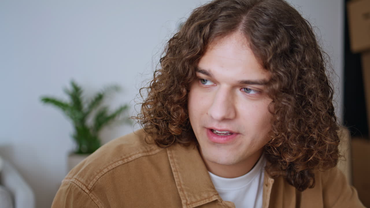 Curly-haired man talking girlfriend in home apartment closeup. Relaxed boyfriend