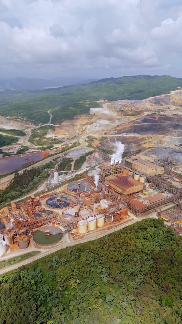 Extensive Barrick Gold open-pit mine in Cotui, industrial landscape of gold and silver extraction, Dominican Republic. Aerial forward, vertical format, copy space