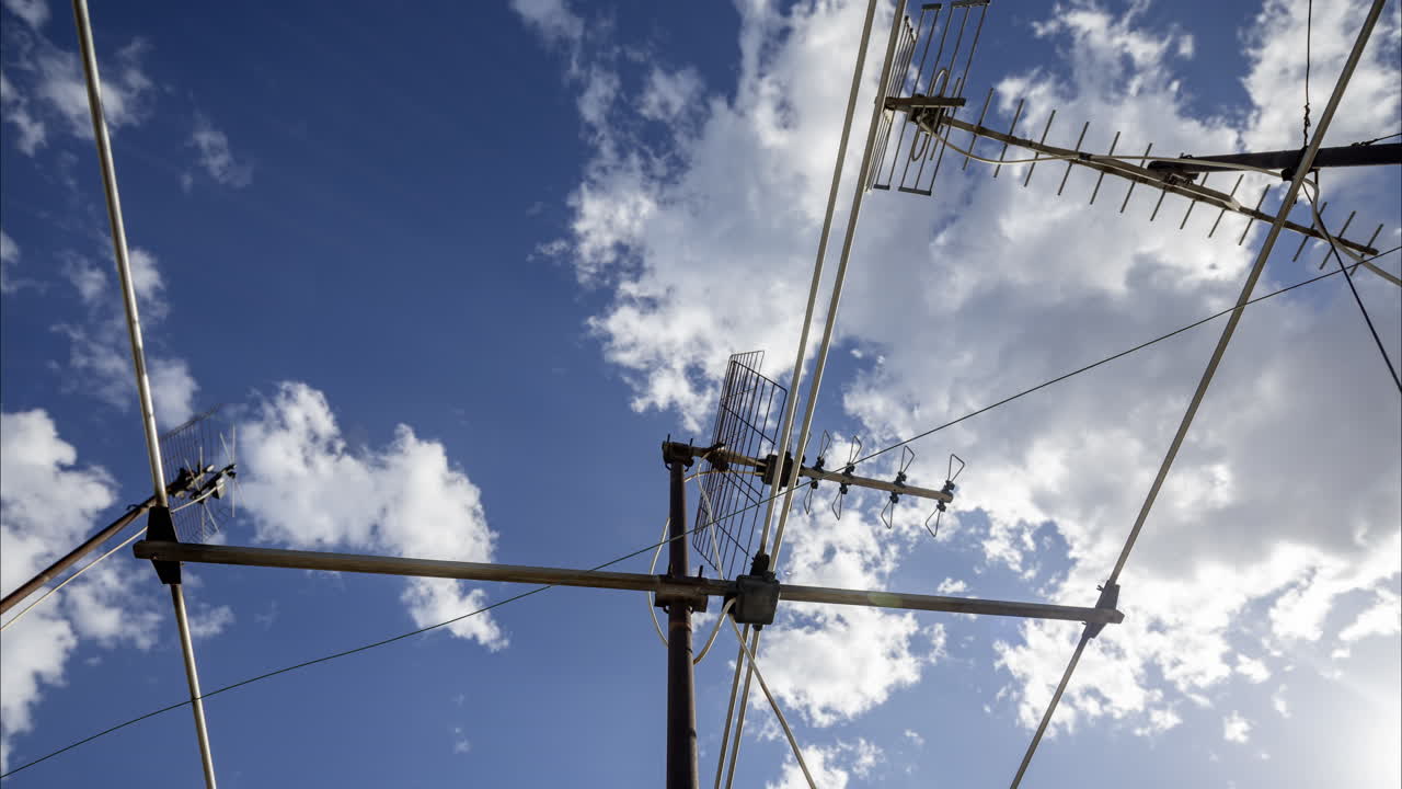 A timelapse of the sky and clouds with television aerials in the foreground
