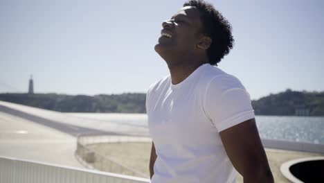 el atleta sonriente cansado después del entrenamiento frotando la cara al aire libre.