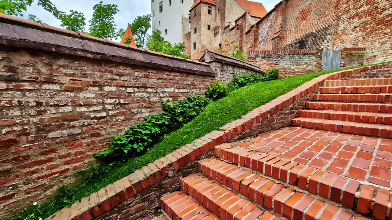 Brick steps lead toward Trausnitz Castle surrounded by historic walls in Landshut