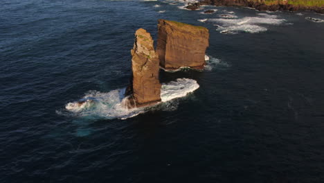 mosteiros beach on the island of sao miguel: drone shot in orbit over the majestic rock formations and the waves breaking at their base