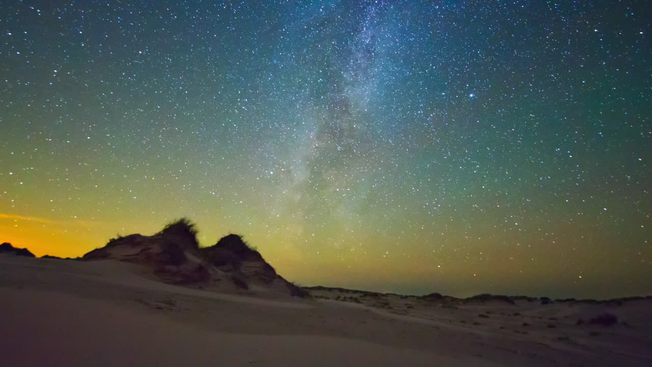 Timelapse of night sky with Milky way over a desert landscape with sand dunes
